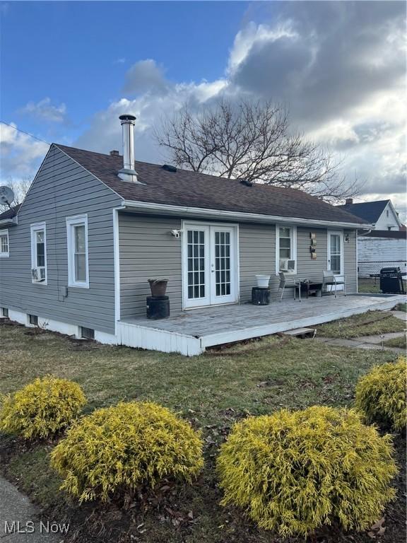 rear view of property with a deck, a yard, french doors, and roof with shingles