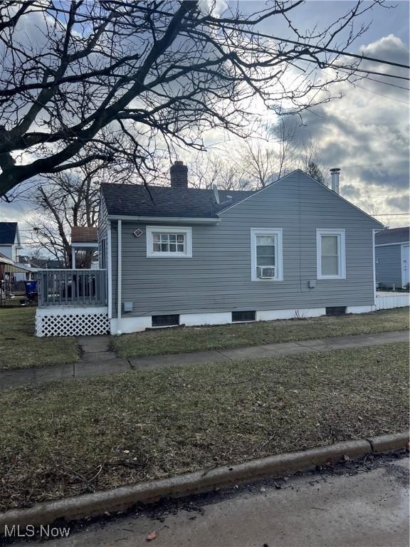 view of side of home with cooling unit, a lawn, a chimney, and a wooden deck