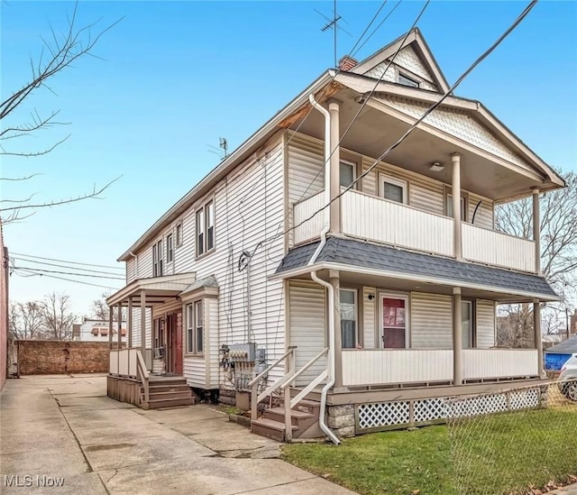 view of front of house featuring a balcony, covered porch, and a shingled roof