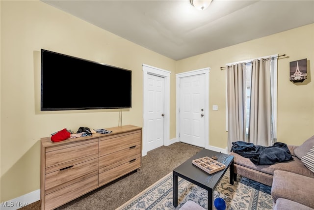 living area with baseboards and dark colored carpet