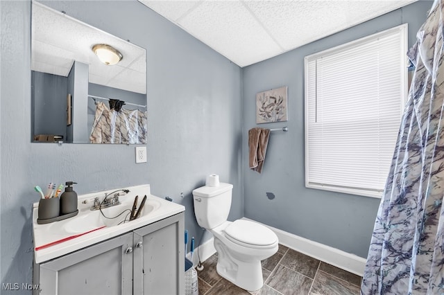 full bath with toilet, baseboards, a drop ceiling, and vanity