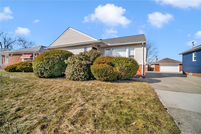 single story home with a garage, brick siding, a front lawn, and an outdoor structure