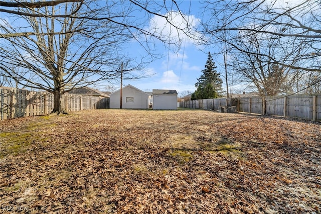 view of yard featuring an outbuilding, a fenced backyard, and a storage unit