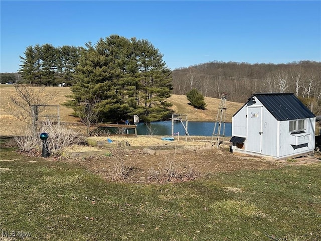 view of yard featuring an outbuilding, a storage shed, and a water view