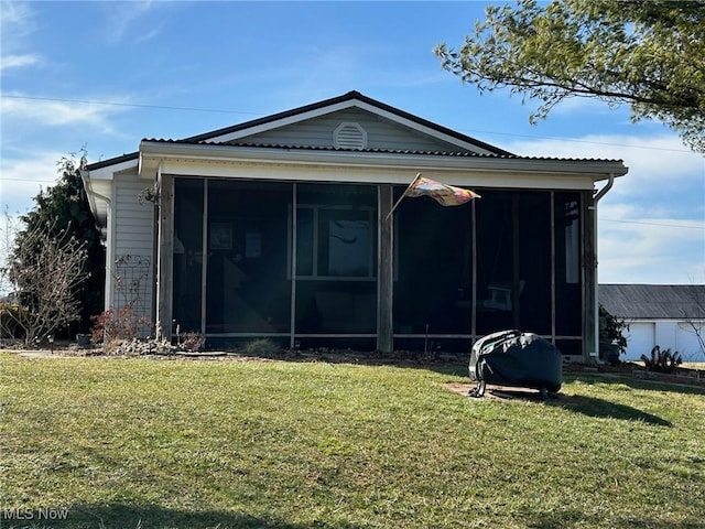 back of property featuring a sunroom and a lawn