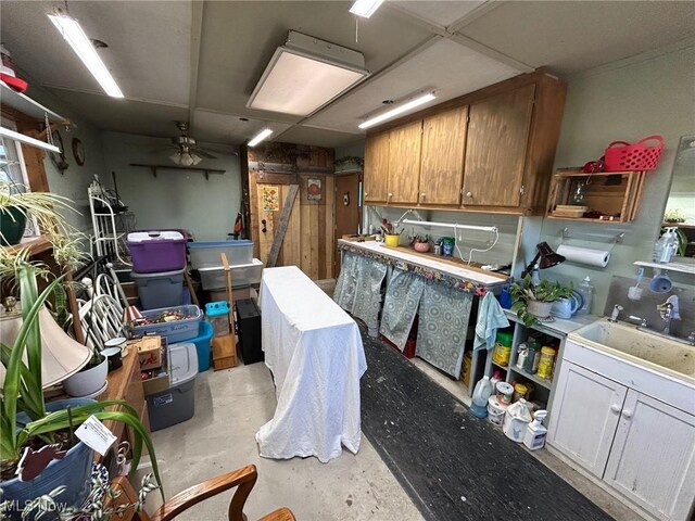 kitchen featuring concrete flooring, ceiling fan, brown cabinetry, and a sink