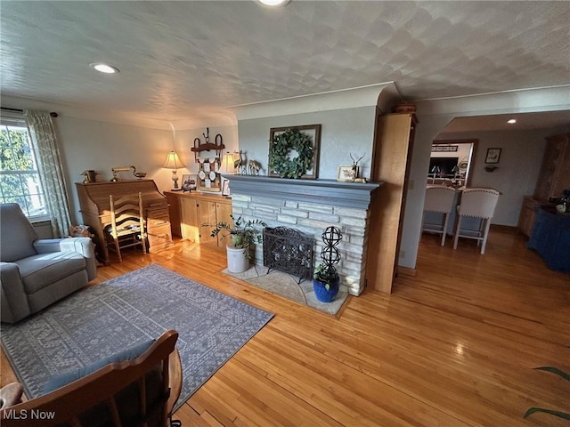 living room with a fireplace, a textured ceiling, and wood finished floors