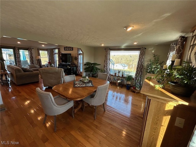 dining space with a textured ceiling, hardwood / wood-style flooring, and a healthy amount of sunlight