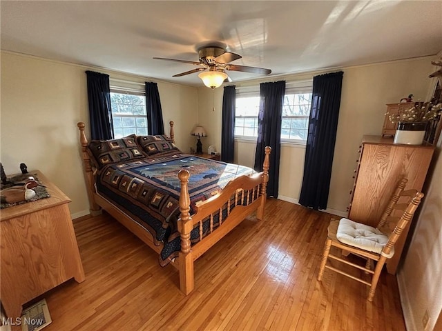 bedroom with light wood-type flooring, ceiling fan, multiple windows, and baseboards