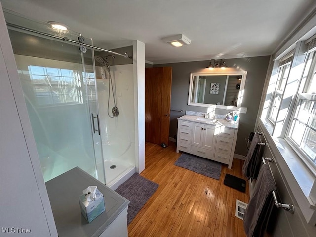 full bathroom with a shower stall, visible vents, wood finished floors, and vanity