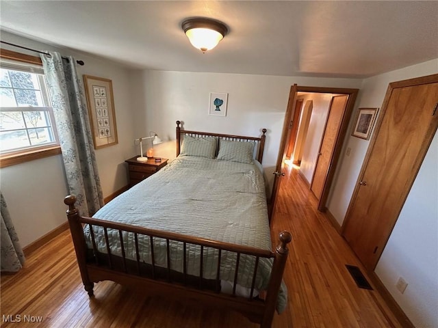 bedroom featuring baseboards, visible vents, and light wood finished floors