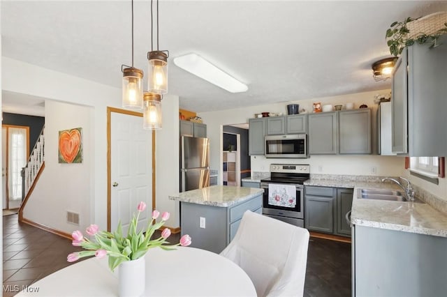 kitchen featuring a kitchen island, a sink, visible vents, appliances with stainless steel finishes, and gray cabinets