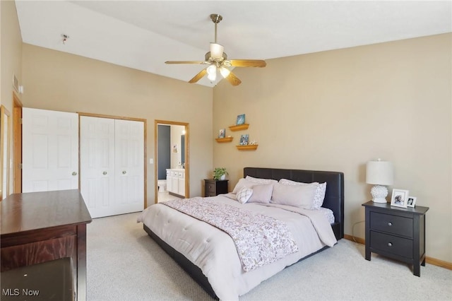 bedroom featuring ensuite bathroom, carpet flooring, baseboards, vaulted ceiling, and a closet