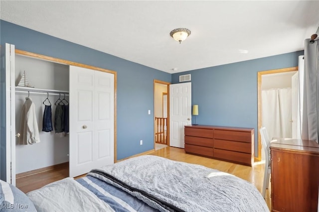 bedroom featuring visible vents, a closet, baseboards, and wood finished floors