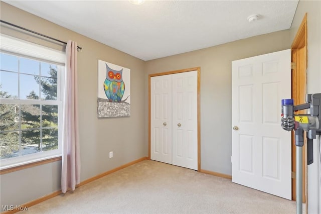 bedroom with baseboards, a closet, and light colored carpet