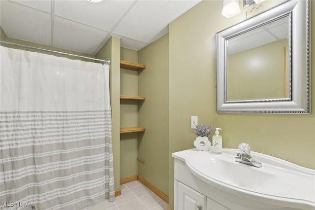 bathroom featuring a drop ceiling, tile patterned flooring, vanity, and baseboards