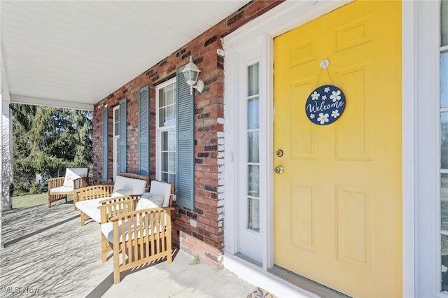 property entrance featuring a porch and brick siding