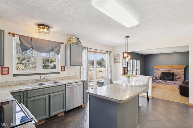 kitchen with a fireplace, stainless steel dishwasher, open floor plan, a sink, and dark tile patterned flooring