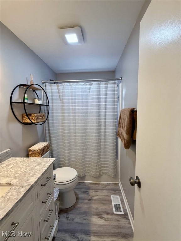 full bath featuring toilet, wood finished floors, vanity, visible vents, and shower / bathtub combination with curtain