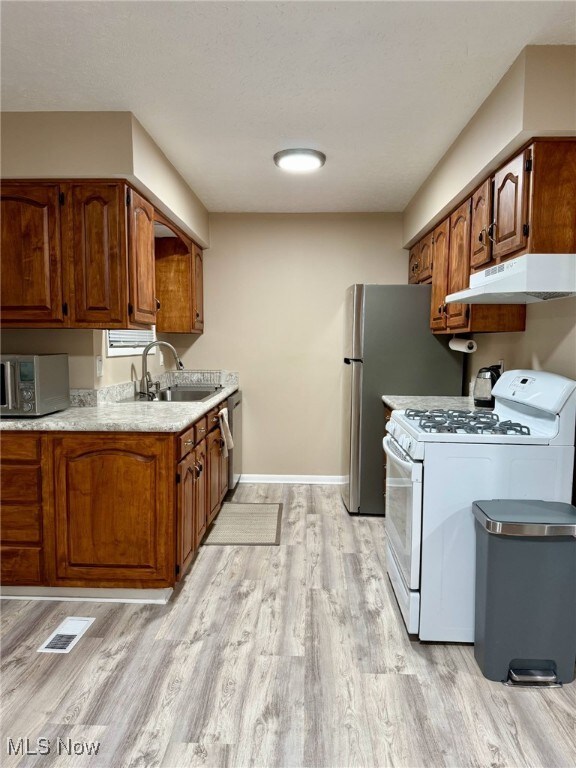 kitchen with stainless steel appliances, light countertops, visible vents, a sink, and under cabinet range hood