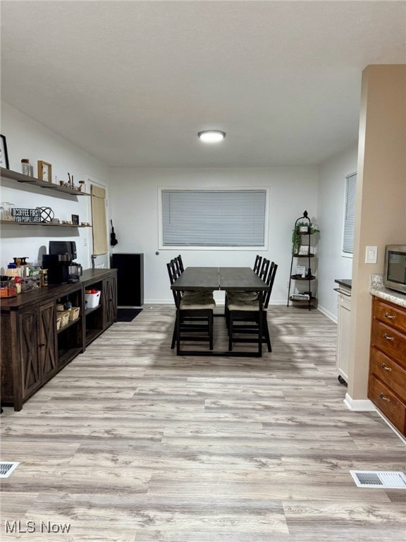 dining space featuring baseboards, visible vents, and light wood-style floors