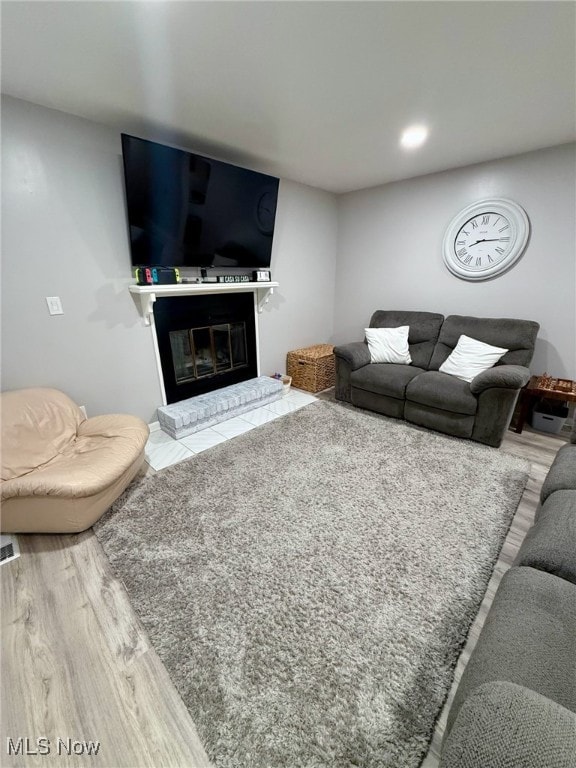 living room featuring a brick fireplace and wood finished floors