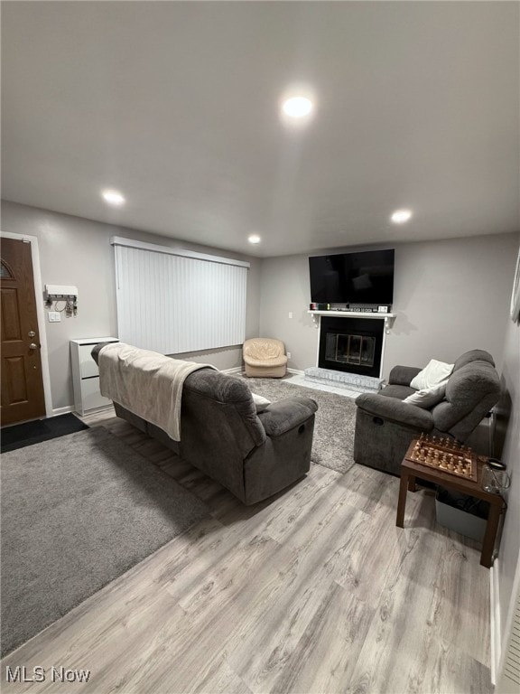 living room with a glass covered fireplace, recessed lighting, and wood finished floors