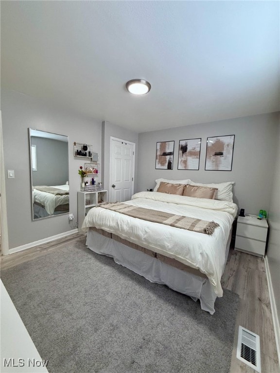 bedroom featuring visible vents, baseboards, and wood finished floors