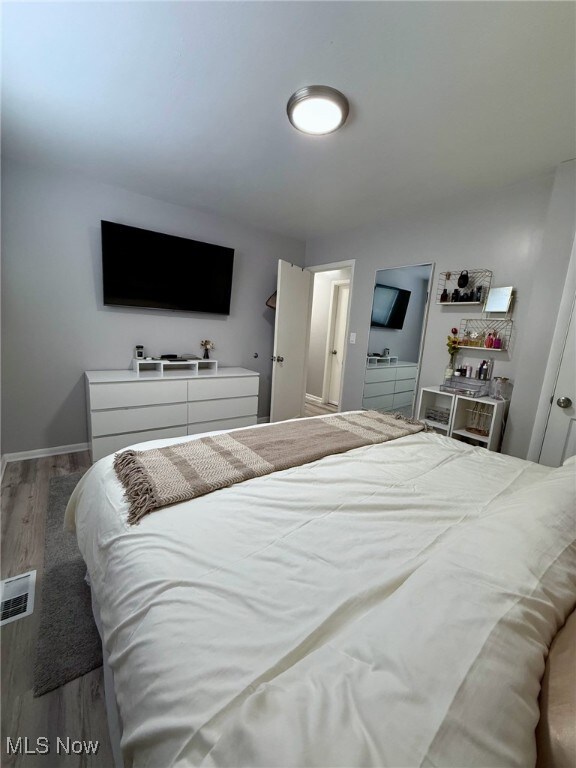 bedroom featuring visible vents, baseboards, and wood finished floors