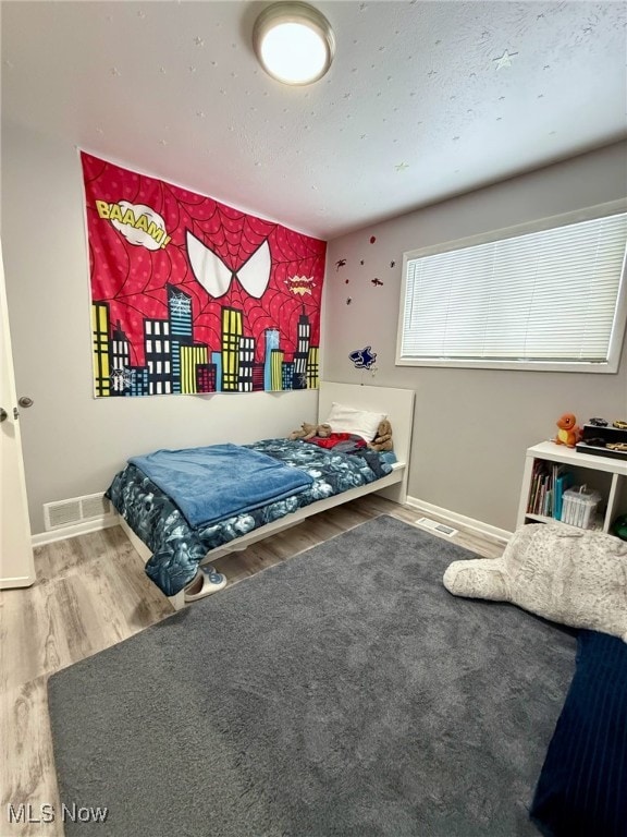 bedroom featuring baseboards, visible vents, and wood finished floors