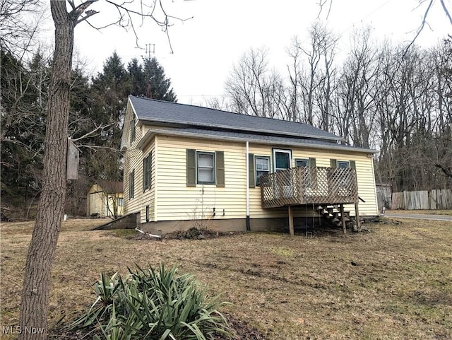 view of front of property with roof with shingles, fence, and a wooden deck