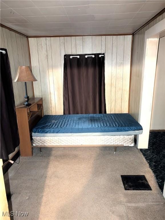 unfurnished bedroom with carpet flooring and wooden walls