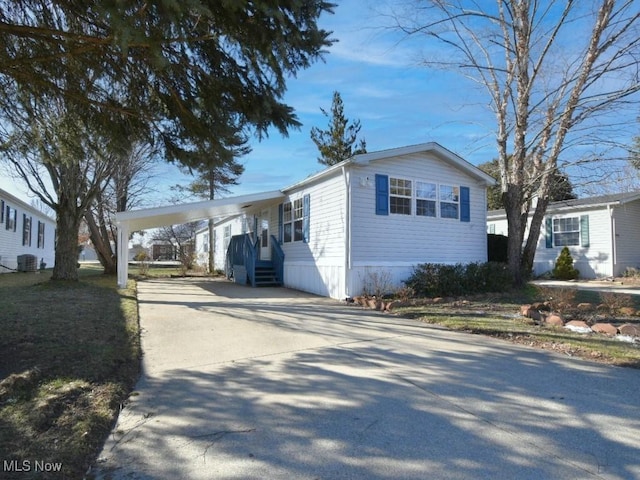 view of side of property featuring cooling unit, an attached carport, and concrete driveway