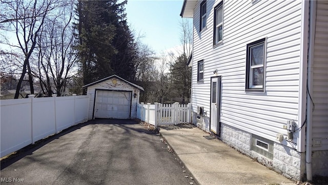 view of property exterior featuring aphalt driveway, an outbuilding, fence, and a detached garage