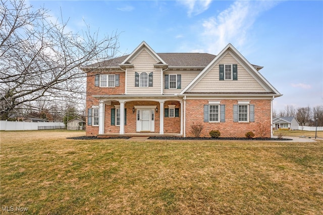 view of front of home with covered porch, brick siding, a front lawn, and fence