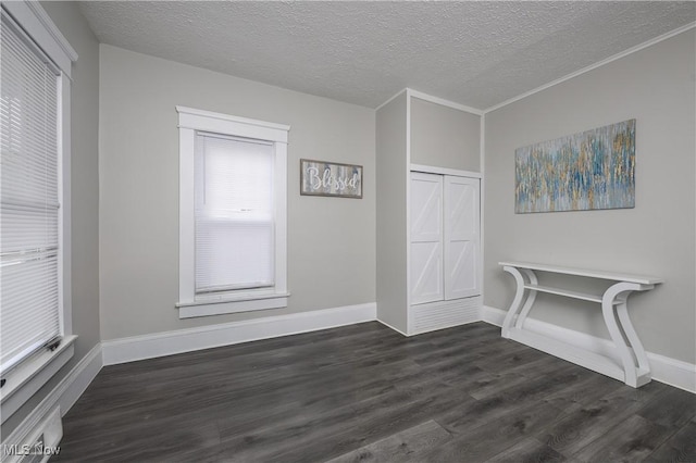 interior space featuring a textured ceiling, dark wood-style flooring, a closet, and baseboards