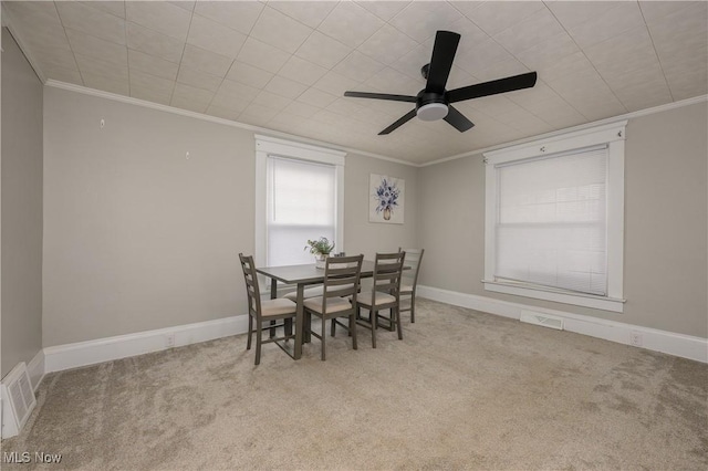 carpeted dining area featuring baseboards, visible vents, and crown molding