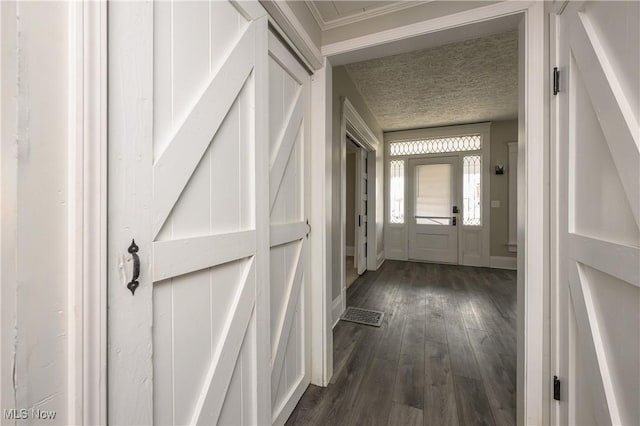 hall with a textured ceiling, dark wood-style flooring, and baseboards