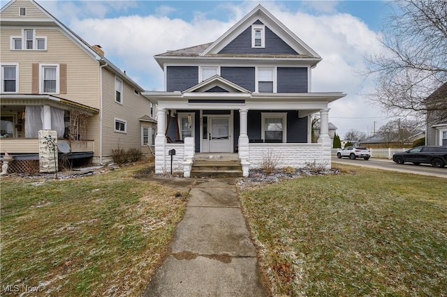 american foursquare style home featuring covered porch and a front yard