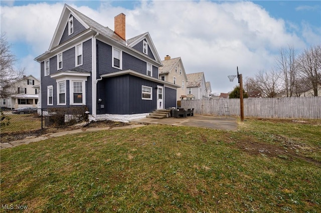 rear view of house with a yard, a fenced backyard, a chimney, and a patio