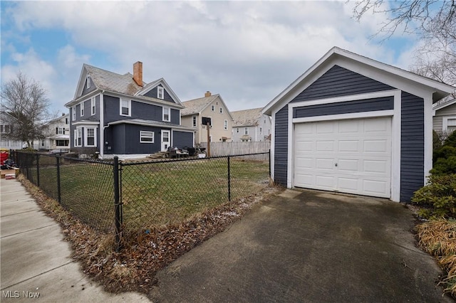 view of front of house with a detached garage, fence, a front lawn, driveway, and an outdoor structure