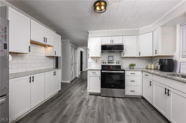 kitchen featuring tasteful backsplash, white cabinets, light stone counters, appliances with stainless steel finishes, and dark wood-type flooring