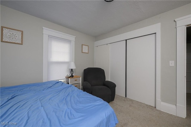 carpeted bedroom with a textured ceiling and a closet