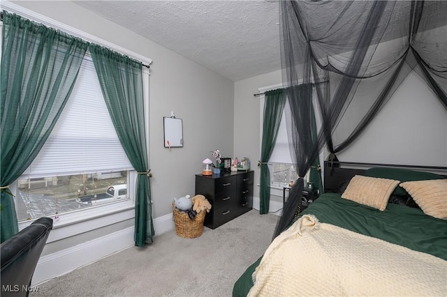 bedroom with a textured ceiling, multiple windows, baseboards, and carpet flooring