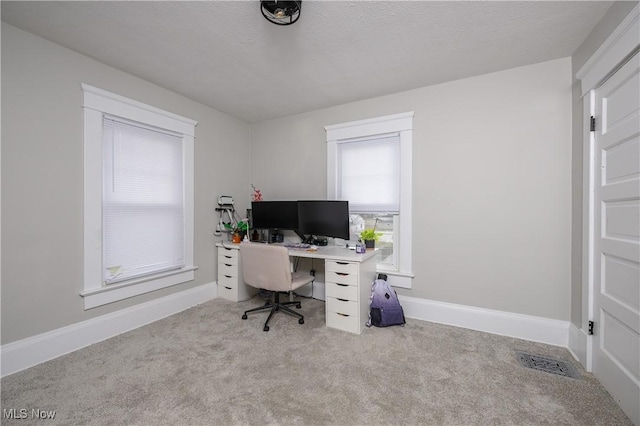 carpeted office space featuring visible vents, a textured ceiling, and baseboards