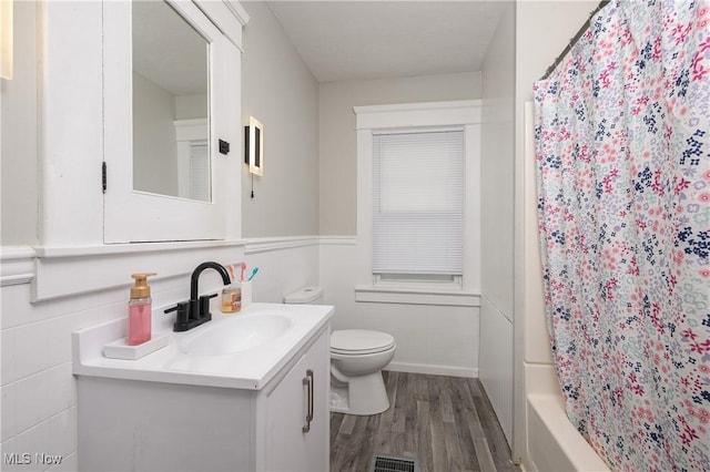 full bath featuring toilet, a wainscoted wall, wood finished floors, vanity, and visible vents