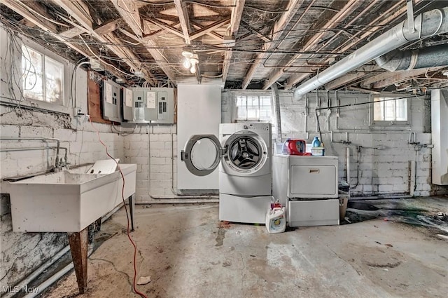 basement featuring washing machine and dryer, electric panel, and a sink