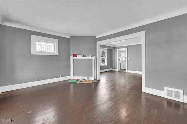 unfurnished living room with baseboards, visible vents, and wood finished floors