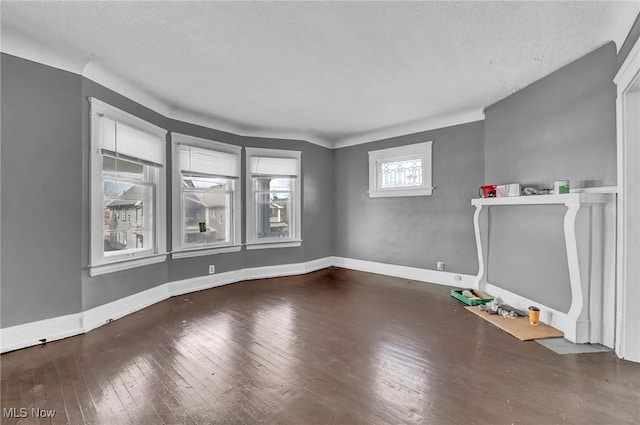 spare room featuring wood-type flooring, a textured ceiling, and baseboards