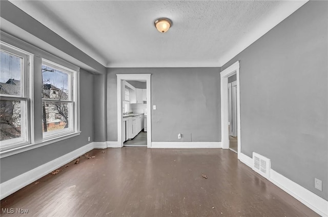 empty room with a textured ceiling, visible vents, and baseboards